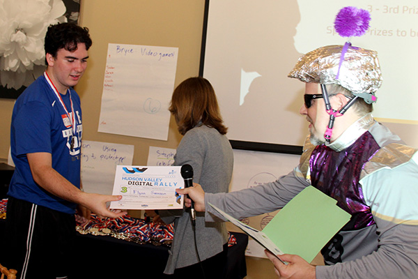 Hackathon participant is awarded his third place certificate by a guy dressed as a robot
